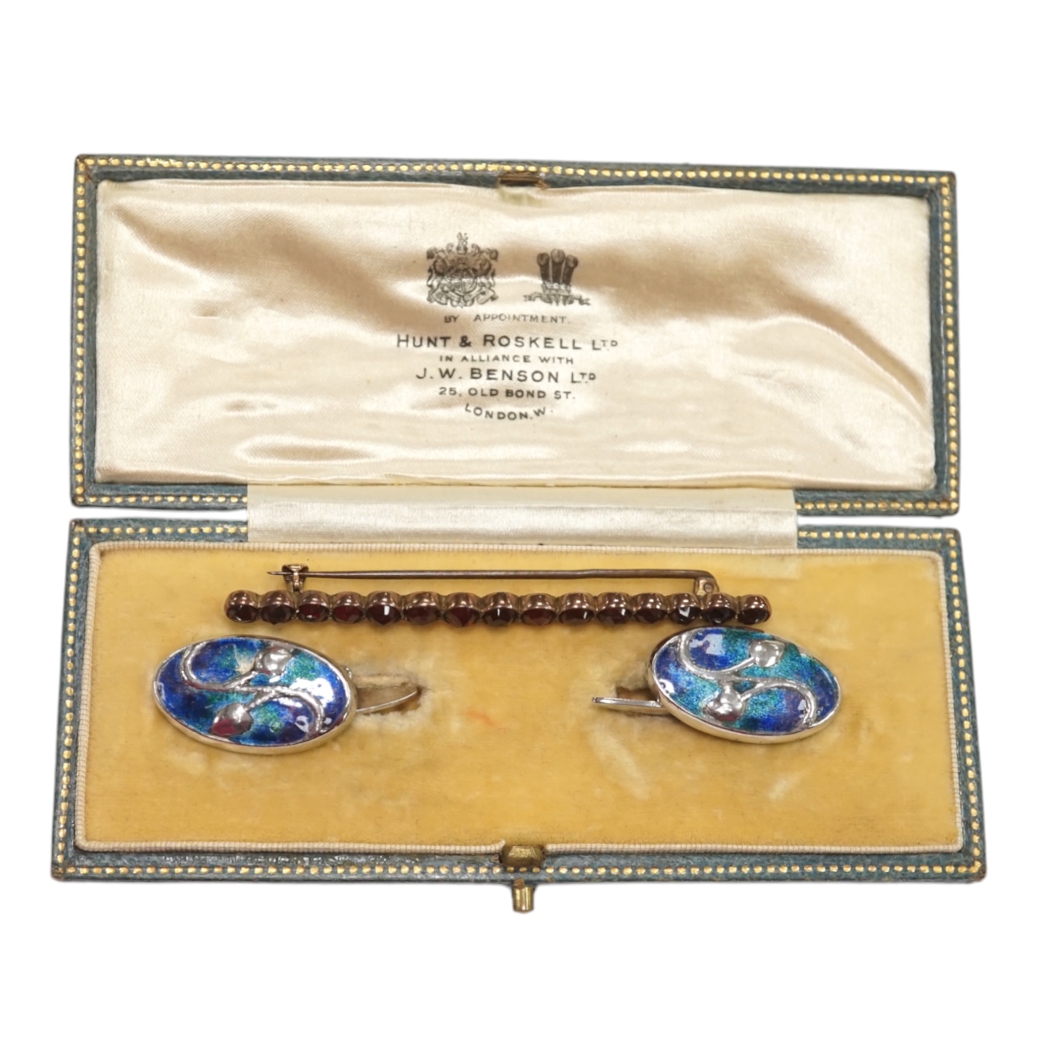 A pair of Edwardian Art Nouveau silver and enamel oval cufflinks, by Liberty & Co Ltd, 23mm, together with a garnet set bar brooch and a Hunt & Roskell box. Condition - poor to fair